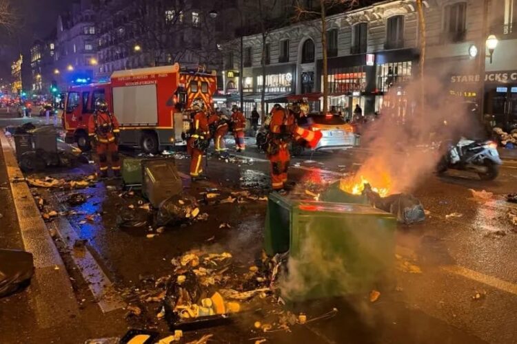 Petugas pemadam kebakaran (damkar) memadamkan tempat sampah yang terbakar pasca demonstrasi menentang reformasi pensiun di Paris, Prancis, (20/03/2023). (Foto: Ant. dari Reuters/Bart Biesemans/as).