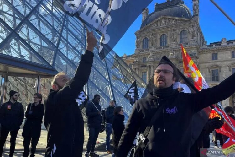 Para pengunjuk rasa memegang bendera serikat pekerja CGT dan Sud Culture Solidaires Prancis berdiri di depan Piramida kaca untuk memblokir pintu masuk Museum Louvre untuk memprotes reformasi pensiun pemerintah Prancis, di Paris, Prancis, Senin (27/03/2023). (Foto: Ant./Reuters-Marco Trujillo/hp).