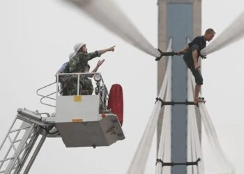 Petugas penyelamat sedang sedang berusaha mengentikan seorang pria yang akan bunuh diri dari atas jembatan Wuhan, provinsi Hubei, China. (Foto: ANT. dari Reuters/Stringer).