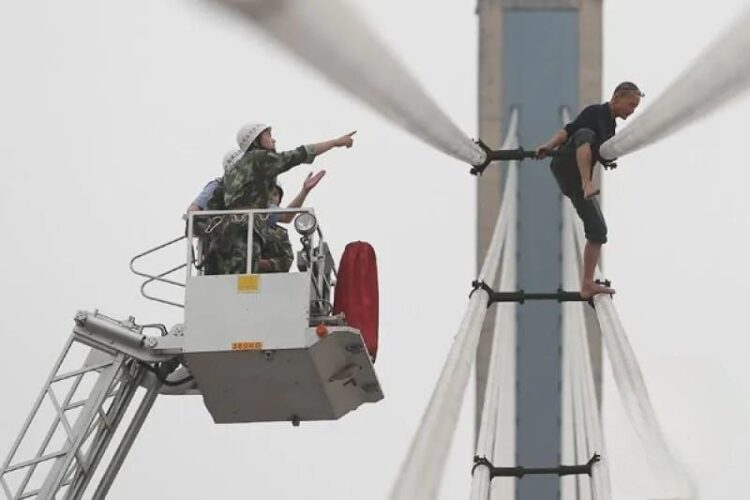 Petugas penyelamat sedang sedang berusaha mengentikan seorang pria yang akan bunuh diri dari atas jembatan Wuhan, provinsi Hubei, China. (Foto: ANT. dari Reuters/Stringer).