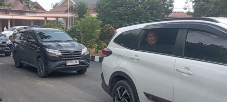 Tampak Bupati Labuhanbatu Erik sempat membuka kaca mobil dan melambaikan tangan kanannya ke sejumlah warga.